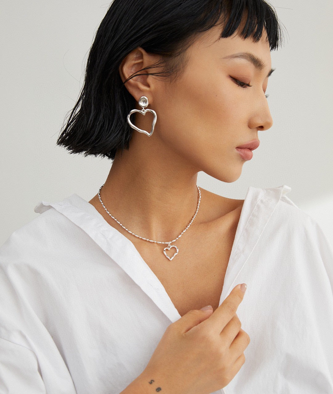 Model displaying Natalia Sterling Silver Heart Necklace as a statement piece, highlighting its individuality and quality craftsmanship